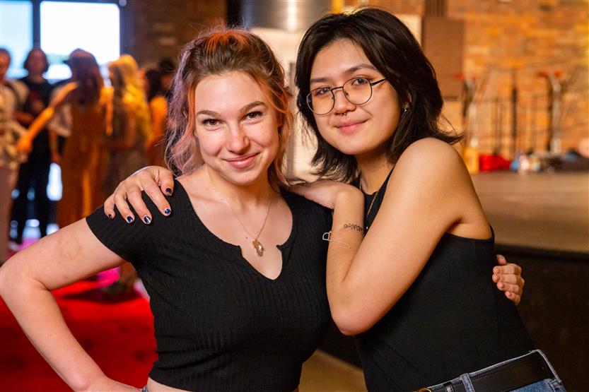Two young women wearing black tops smile
